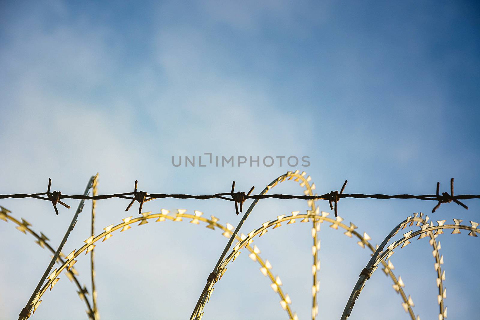 Barbed Wire Fence Used For Protection Purposes Of Property And Imprisonment, No Freedom, Barbed Wire On fence With Blue Sky To Feel Worrying.