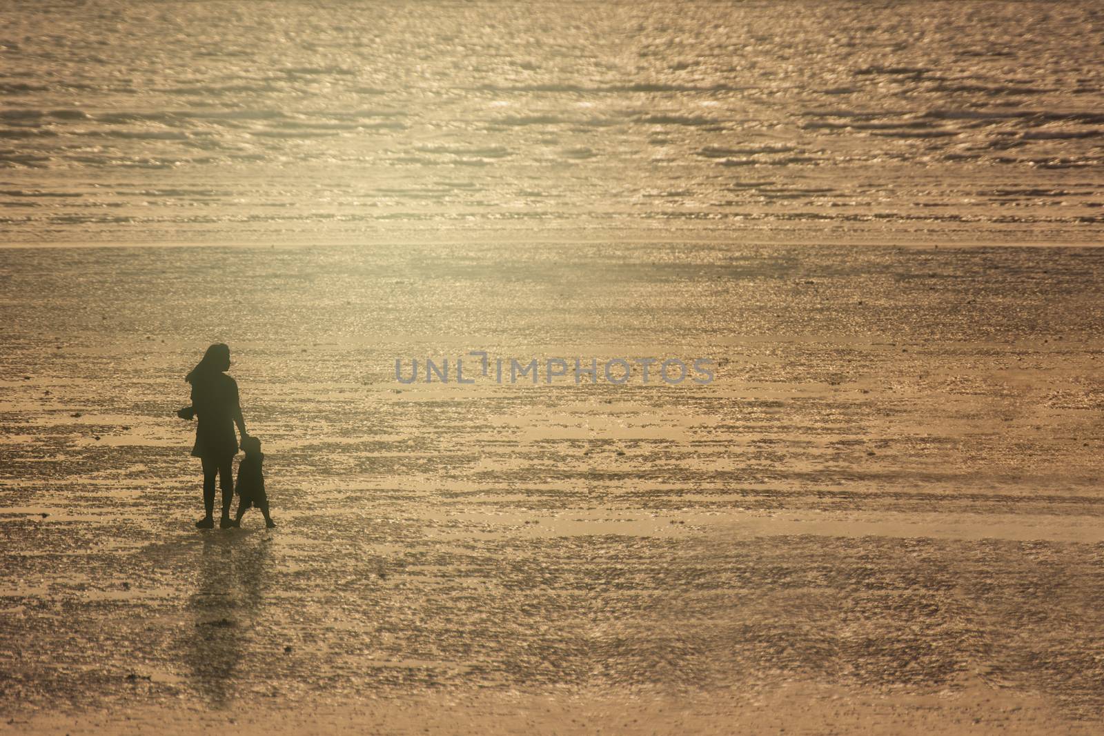 Silhouettes Of Mother And Son On Beach At Sunset. by rakoptonLPN