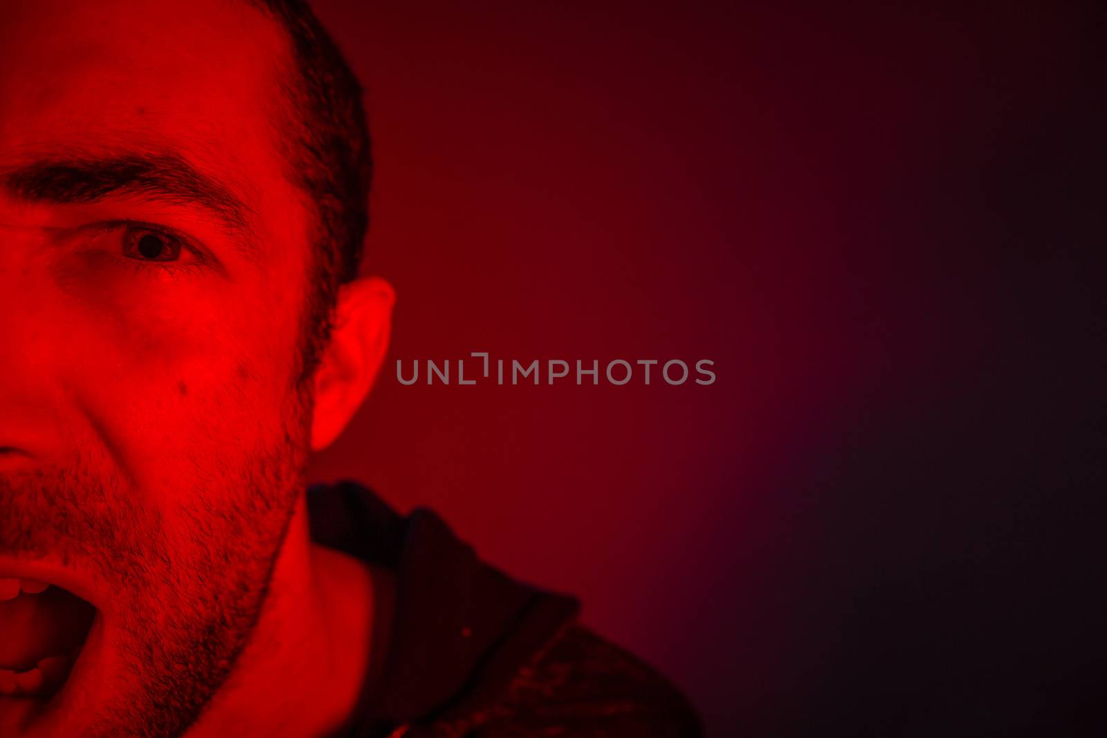 Man with angry facial expression screaming out loud. Close up portrait of a man shouting with mouth wide open.