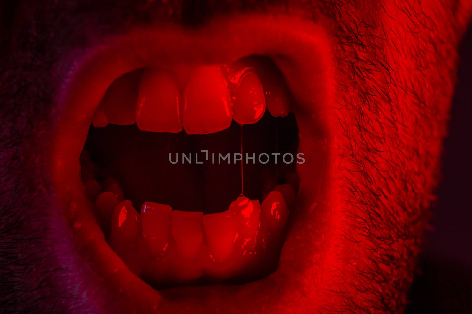 Macro closeup on man shouting with mouth wide open. Portrait with angry facial expression.