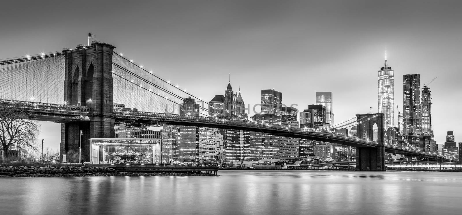 Brooklyn bridge and New York City Manhattan downtown skyline at dusk with skyscrapers illuminated over East River panorama. Panoramic composition.