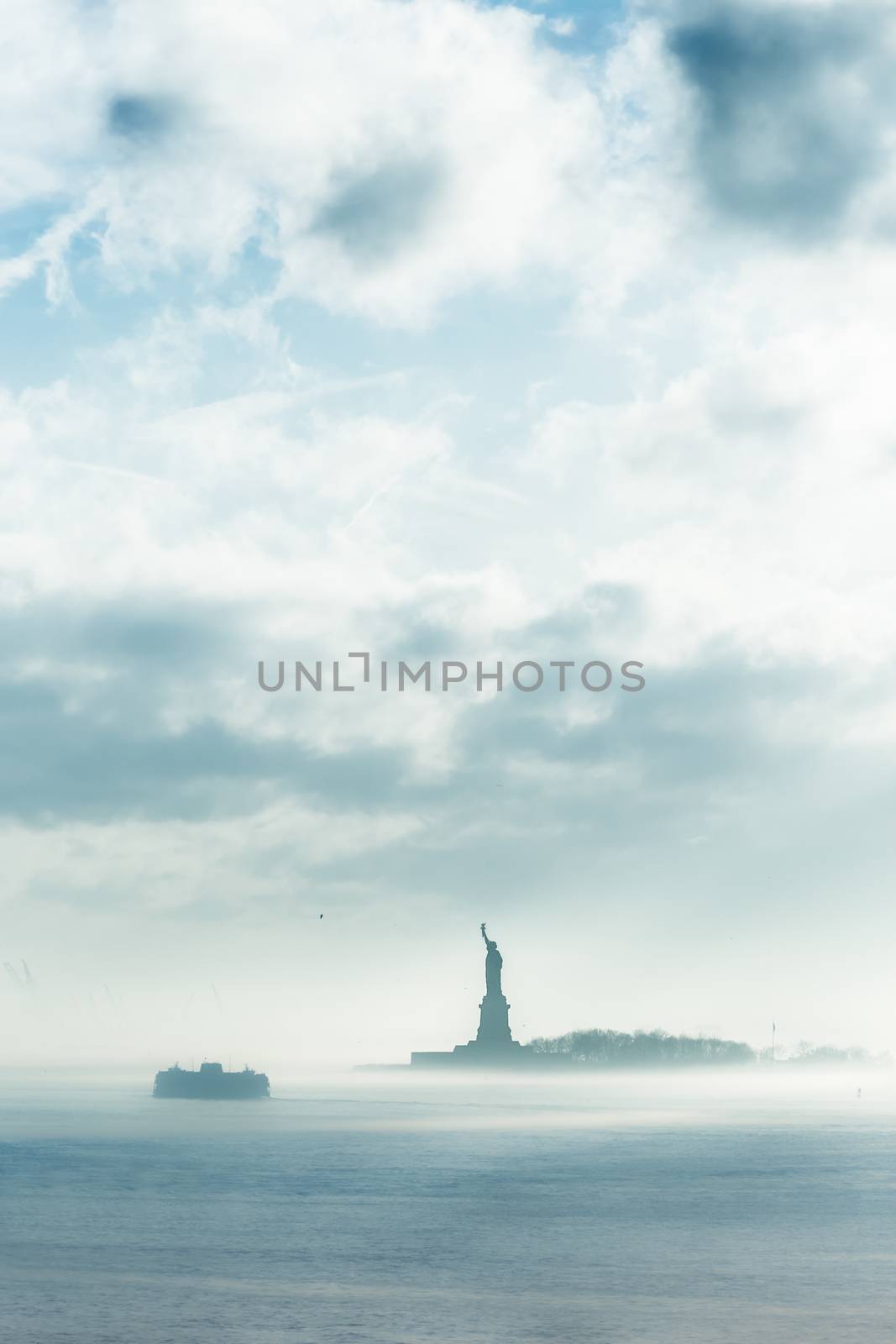 Staten Island Ferry cruises past the Statue of Liberty in dramatic storm. Manhattan, New York City, United States of America. Vertical composition. Copy space.