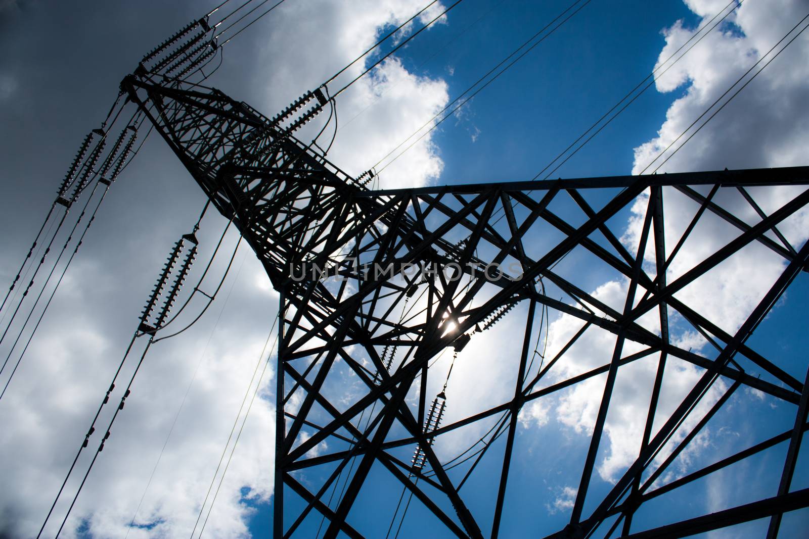 Power line tower taken at an unusual perspective with blue sky and clouds