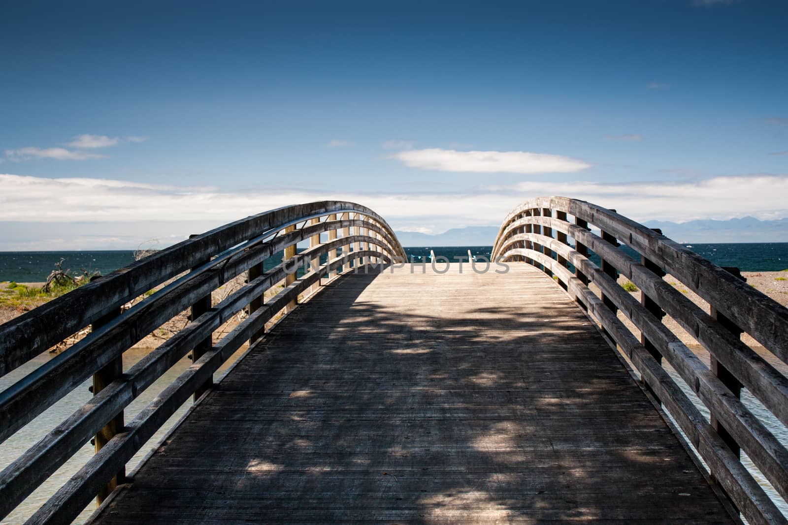 Shaded wooden foot bridge leading to ocean beach