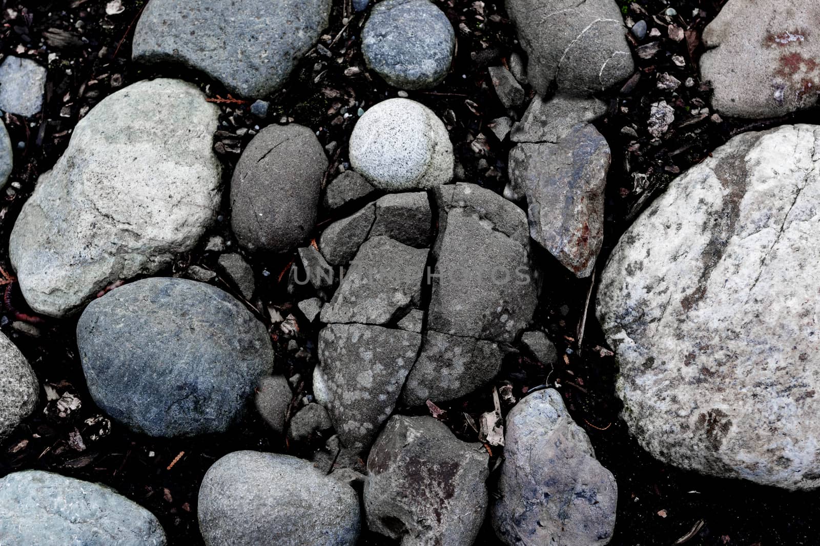 Round river rocks in the ground with a single cracked stone in the center