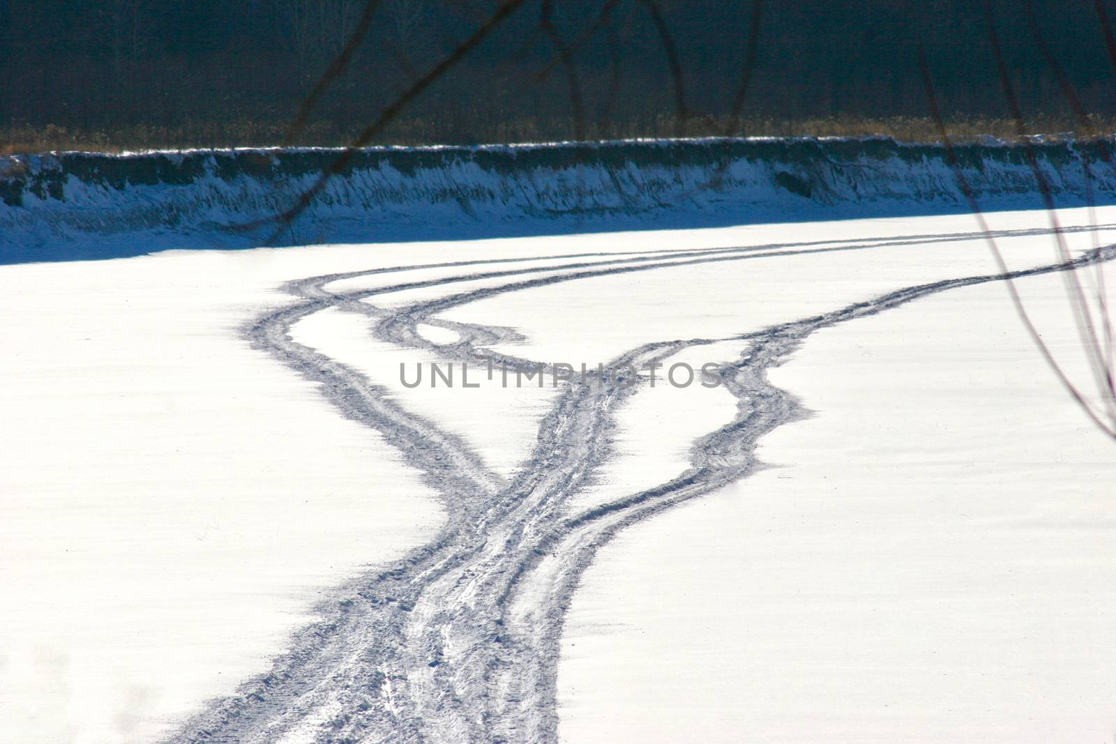 Multiple snowmobile tracks lace together on the frozen snow covered river.
