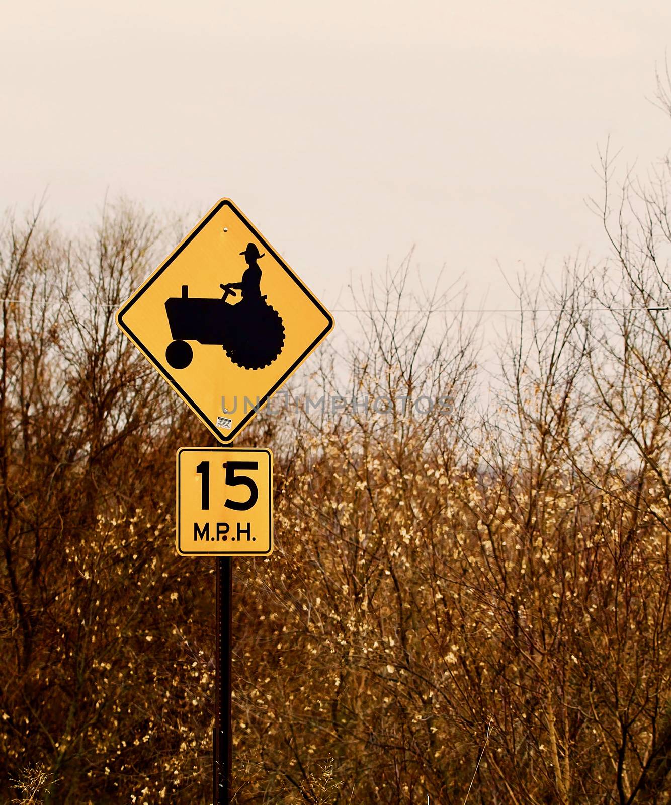 A yellow warning sign for tractors shows with a speed limit sign.