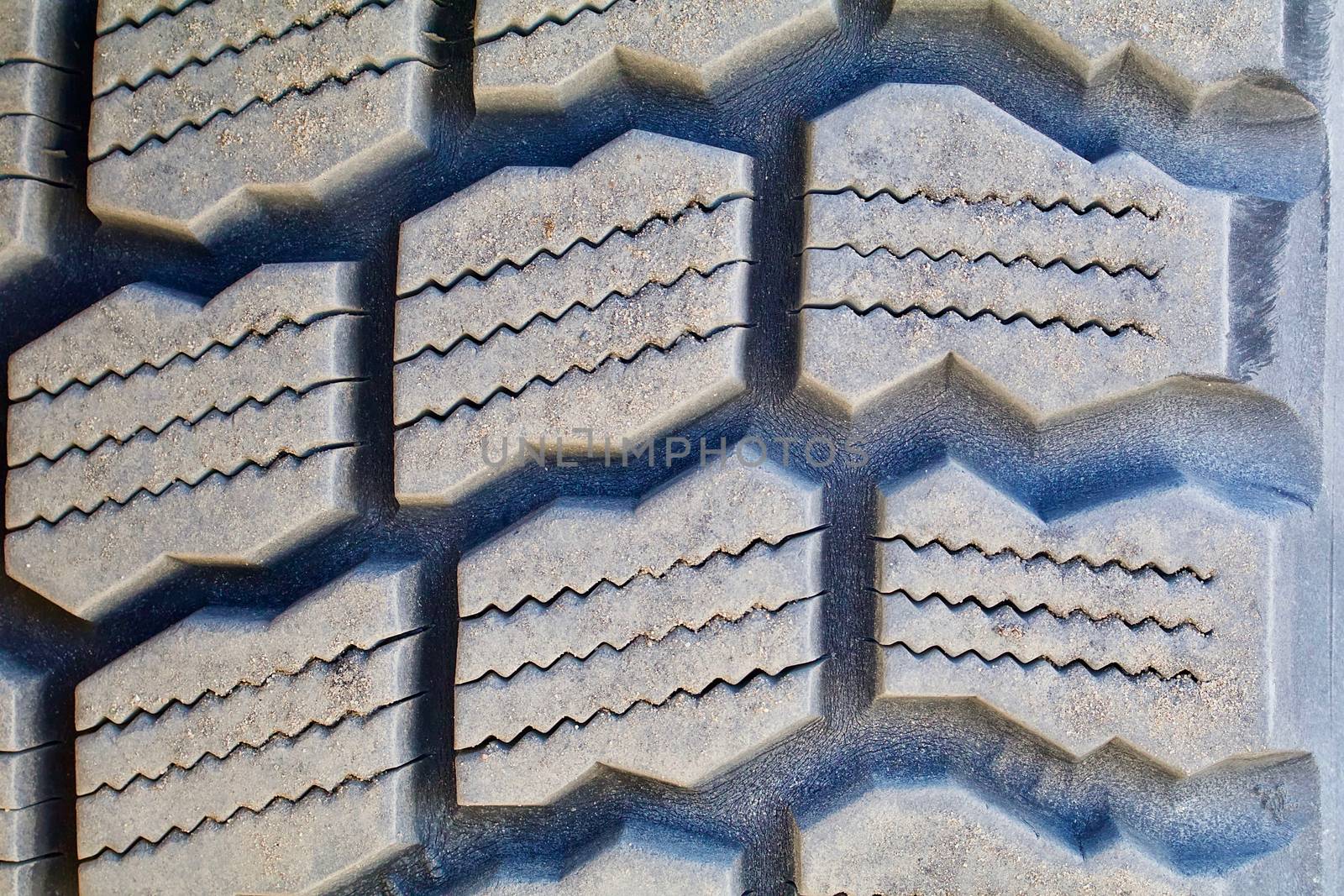 A closeup of a weathered heavy rubber tire tread show.