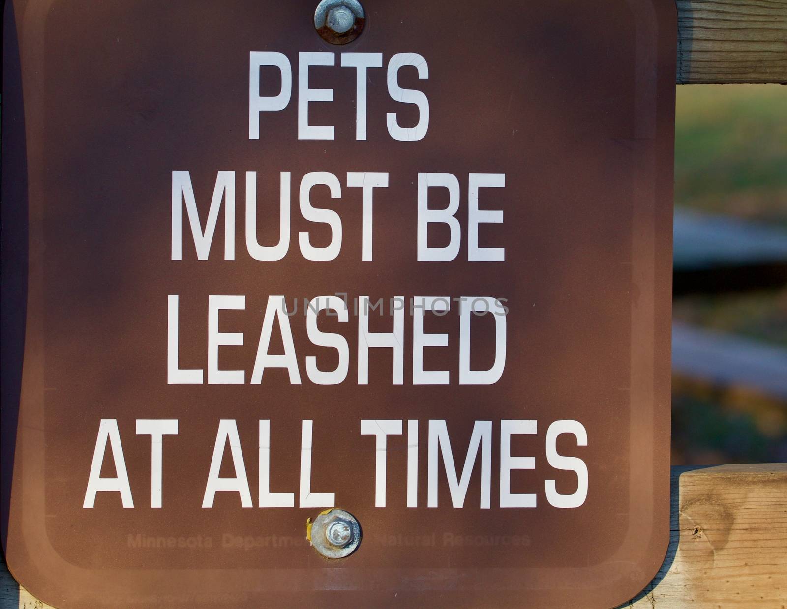 White lettering on brown shows pets must be leased at all times.