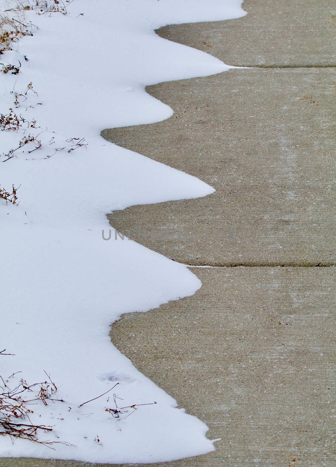 Snow drifts show their curves along the sidewalk.