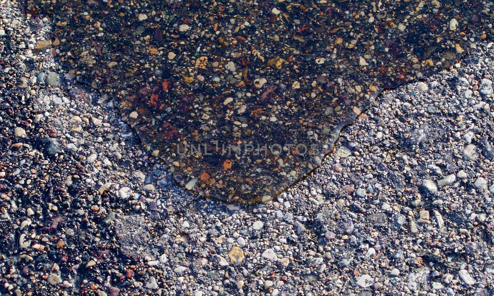 Water slowly rolls across dry asphalt