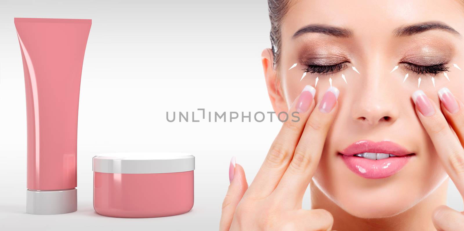 Woman massaging her face with fingers and cosmetics tube and jar on light grey background