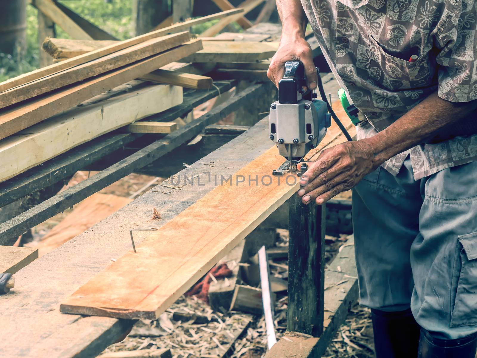 Carpenter cutting wooden panel by using jig saw