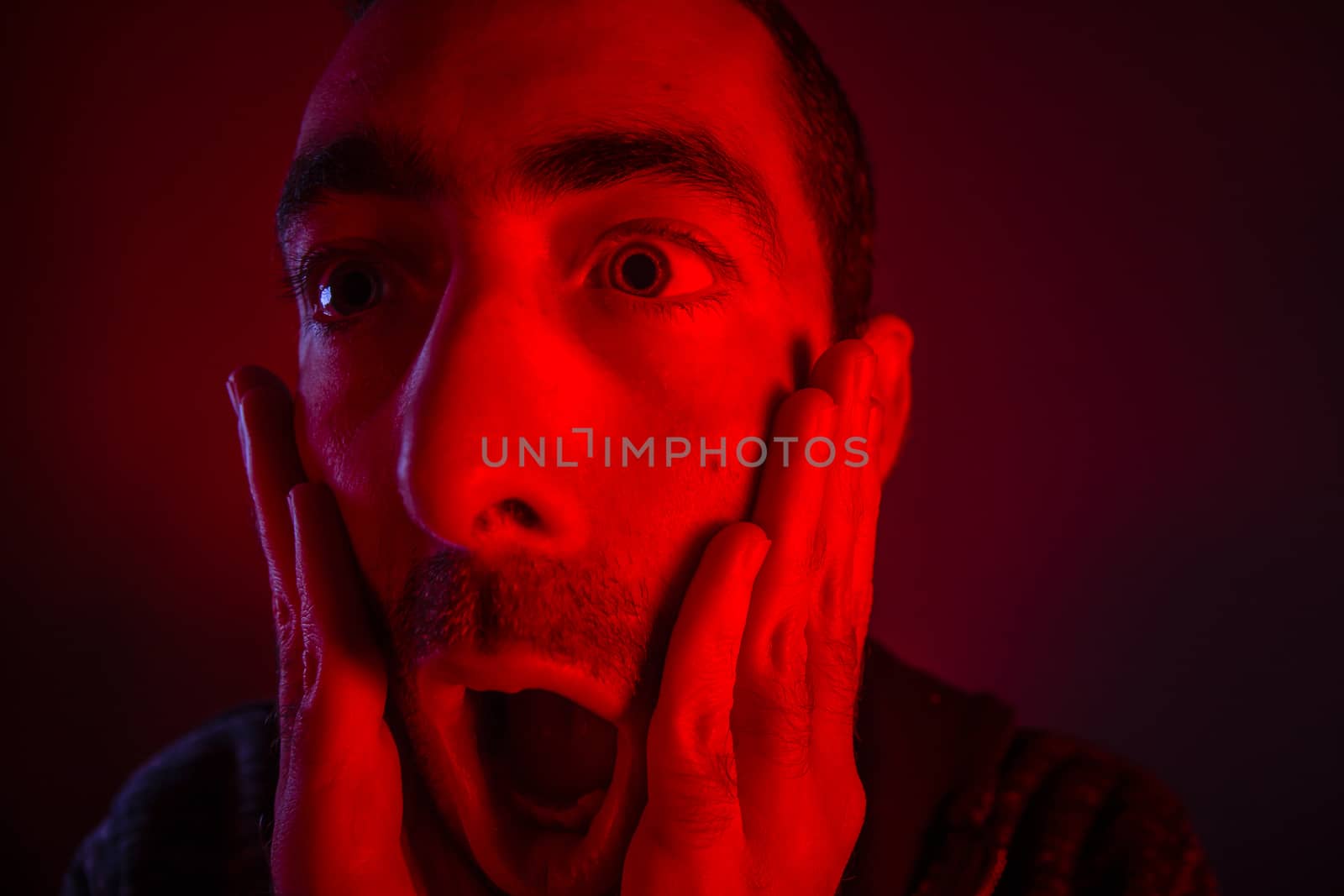 Man with surprised facial expression with opened mouth. Close up headshot portrait of shocked man with his hand on the face.