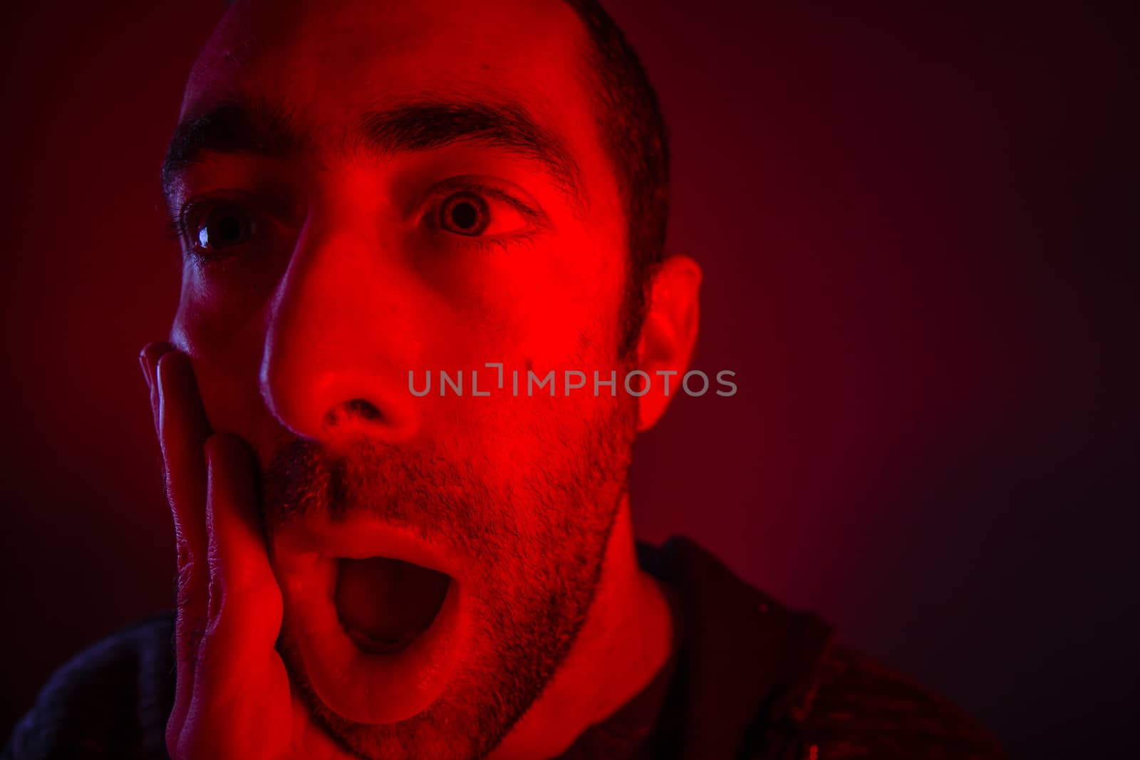 Man with surprised facial expression with opened mouth. Close up headshot portrait of shocked man with his hand on the face.