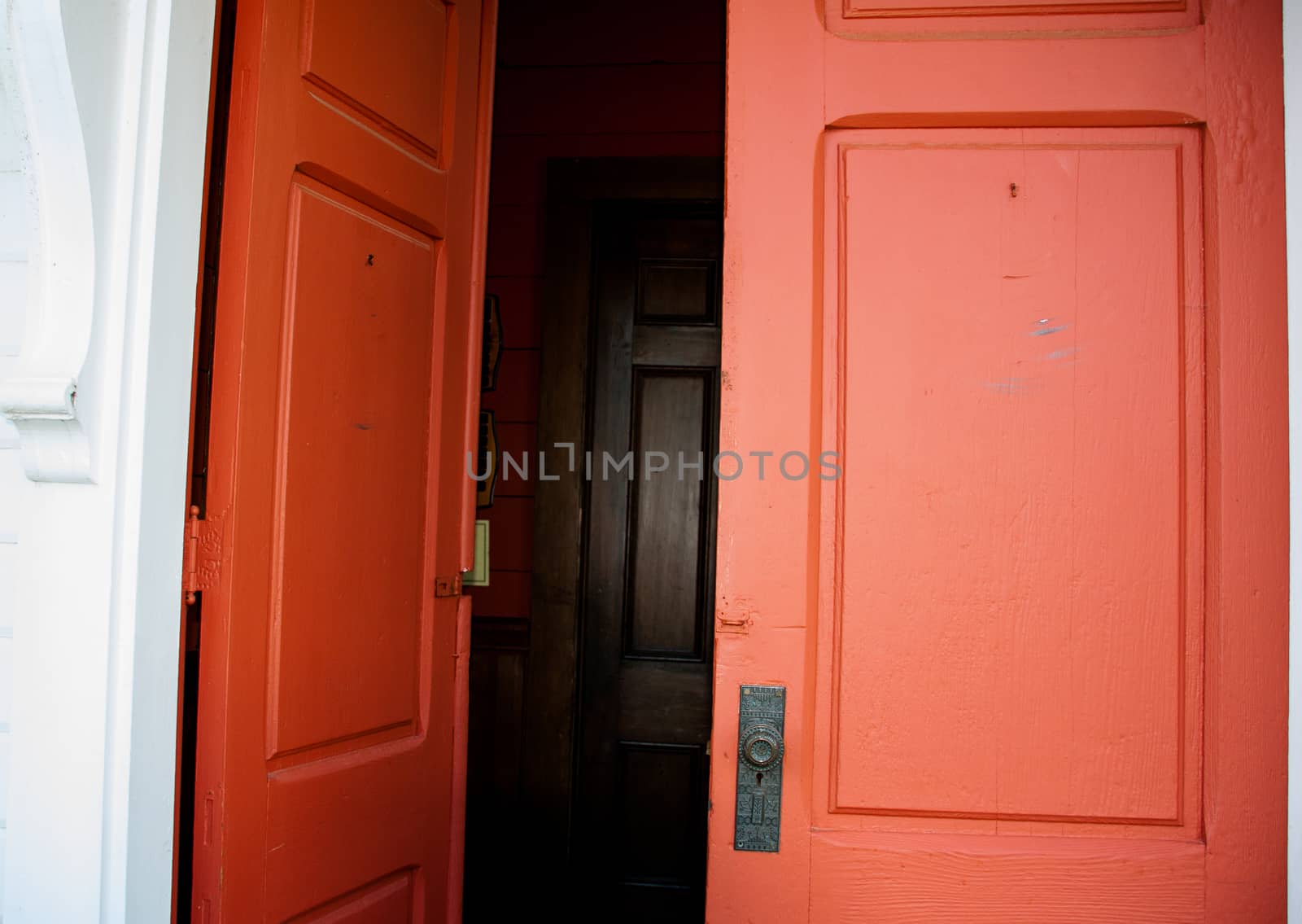 Old wood red double doors leading in to a dark hall by experiencesnw