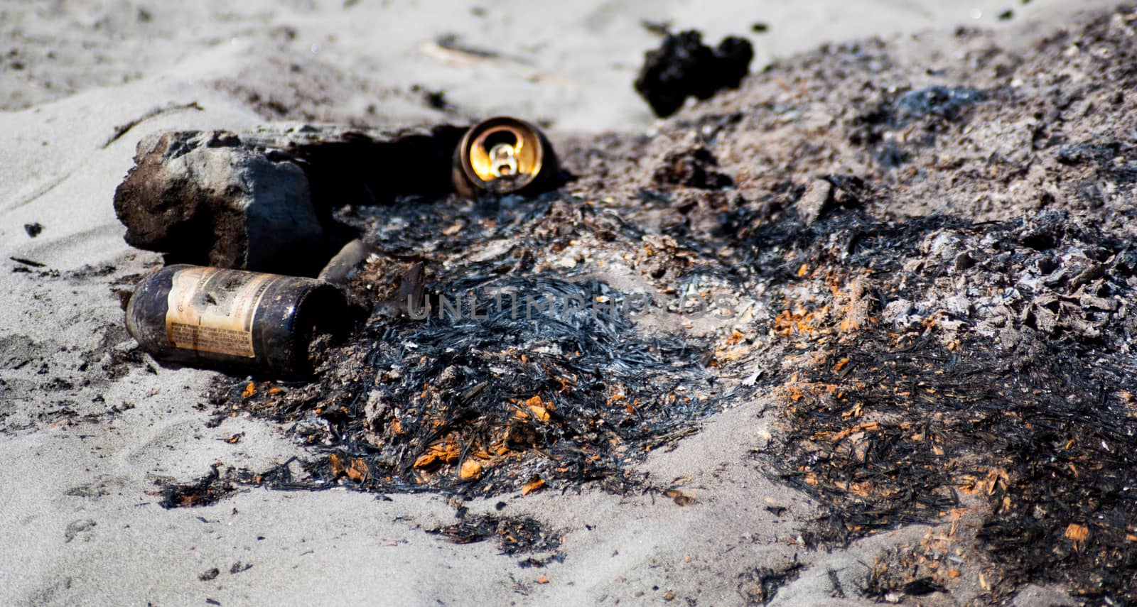 Garbage on a beach camp fire left over from a party by experiencesnw