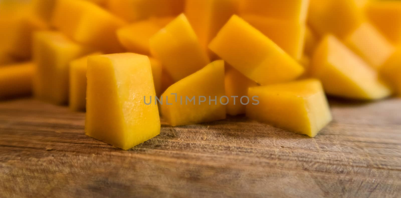 Chopped butternut squash looks like mango texture and color on wood cutting table