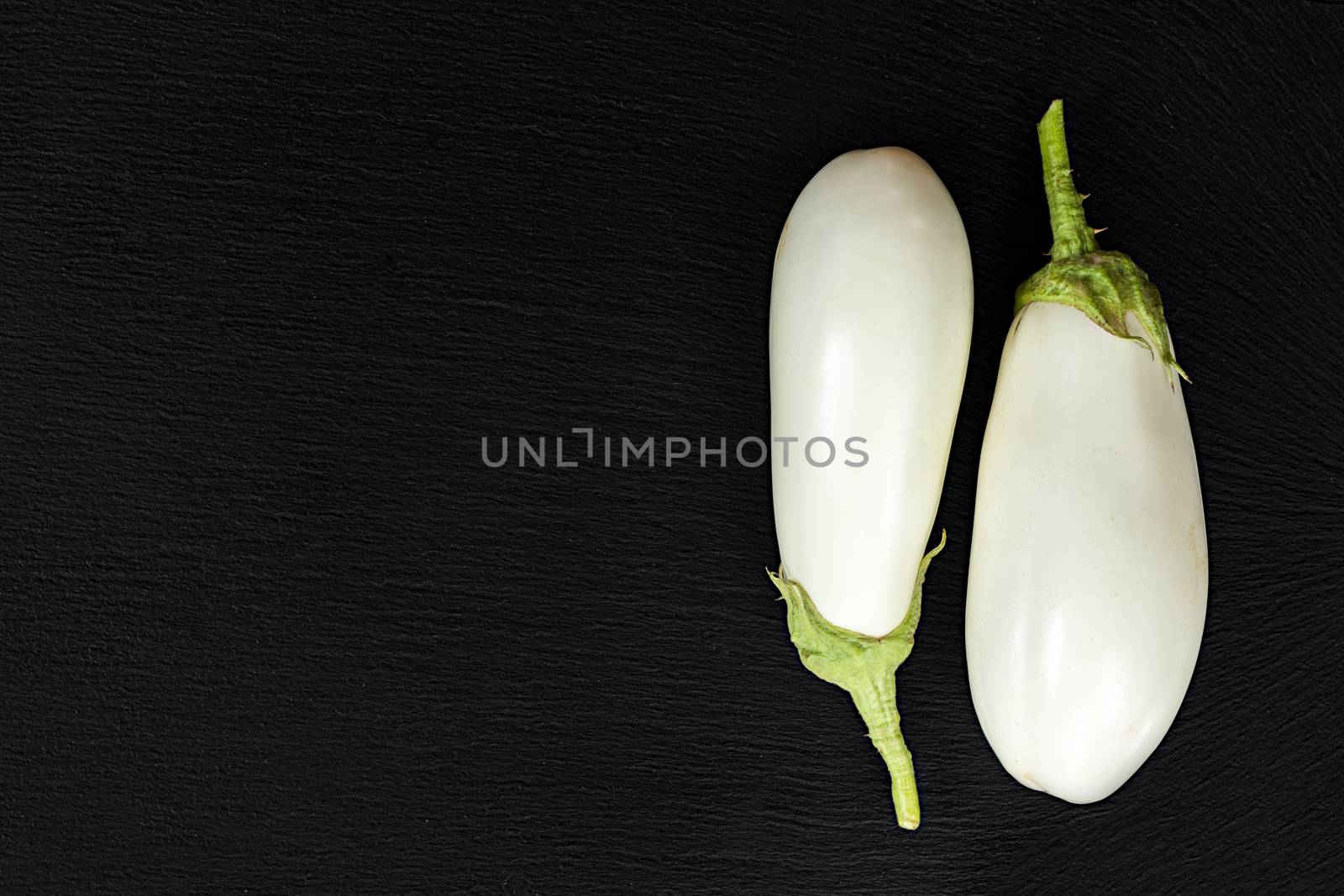 White eggplant on a black stone surface. Top view. Copy space.