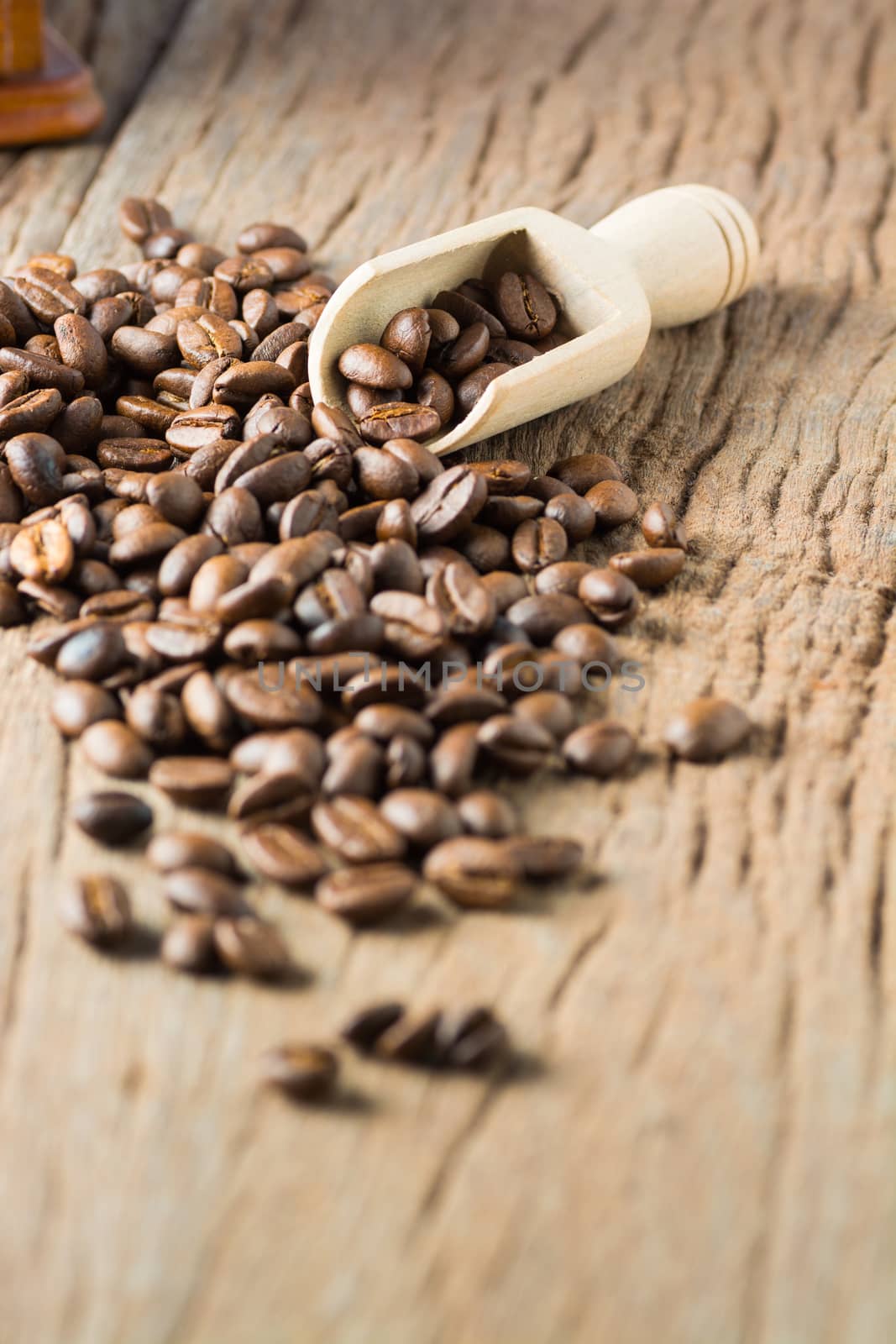 Stack of Fresh Raw Coffee Beans on Wooden Desk Table with Wooden Spoon and Coffee Grinder as Refresh Beverages Concept