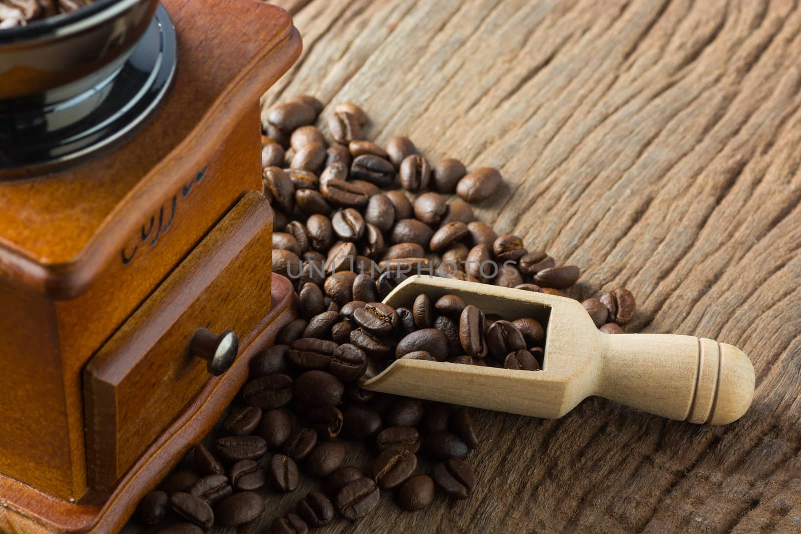 Stack of Fresh Raw Coffee Beans on Wooden Desk Table with Wooden Spoon and Coffee Grinder as Refresh Beverages Concept