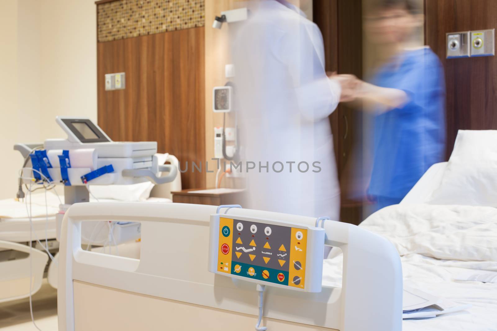 Blurred figures of doctor and a patient in modern hospital room.