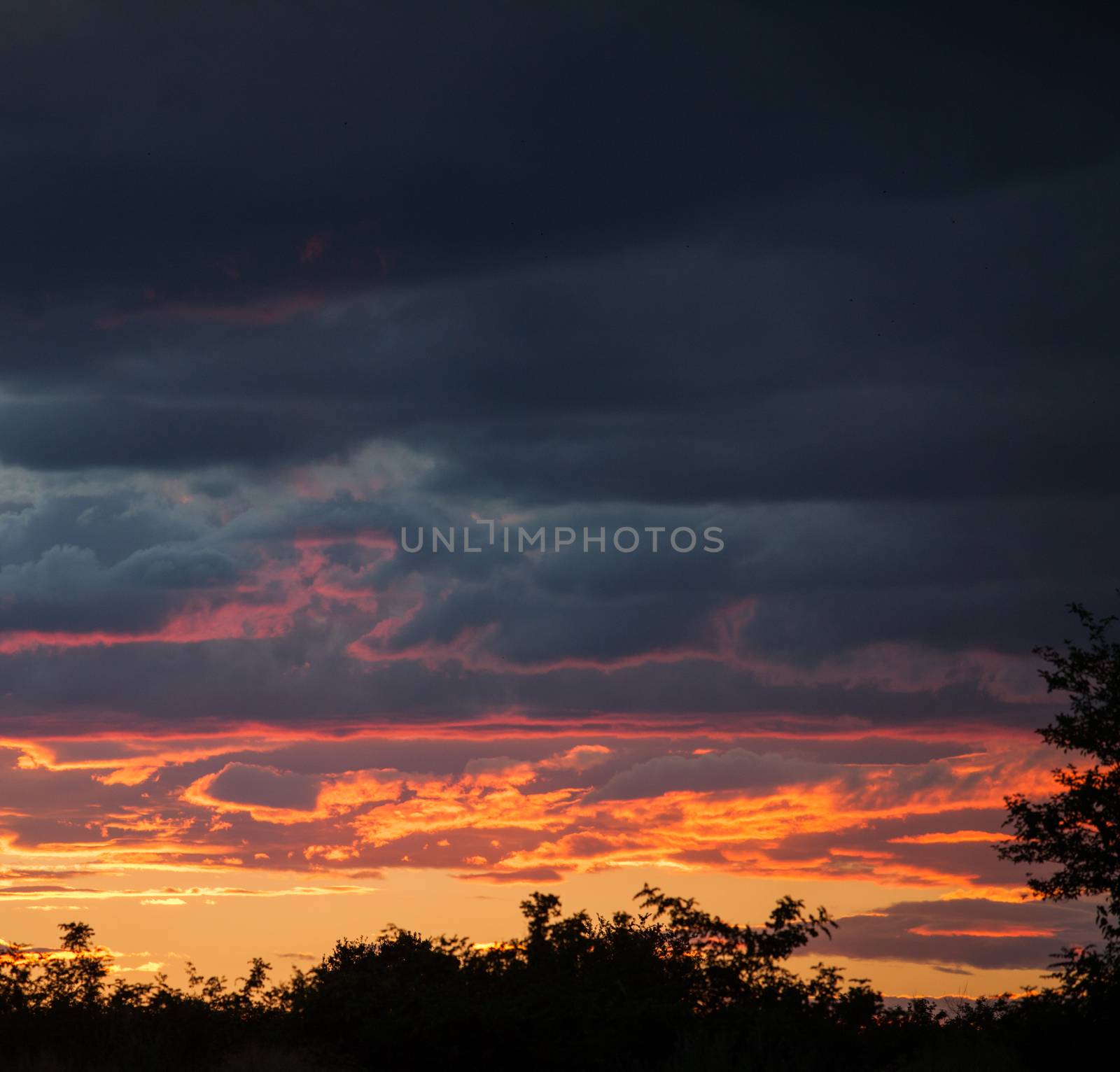 Dramatic clouds in orange, purple and black during sunset.