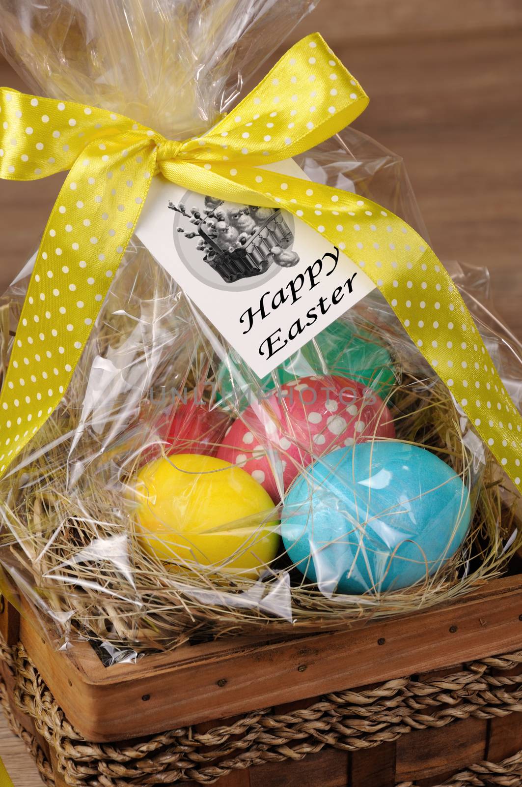Colorful  eggs stacked hay in cellophane gift basket for Easter