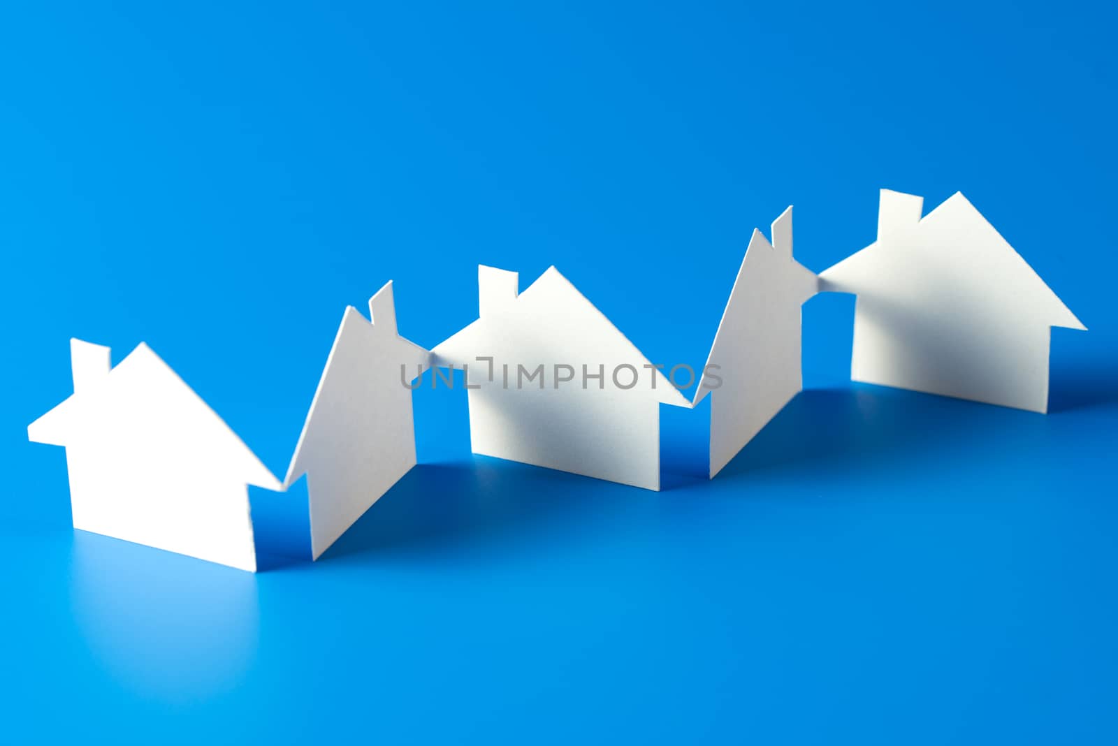 House cut out of paper on blue background by Kenishirotie