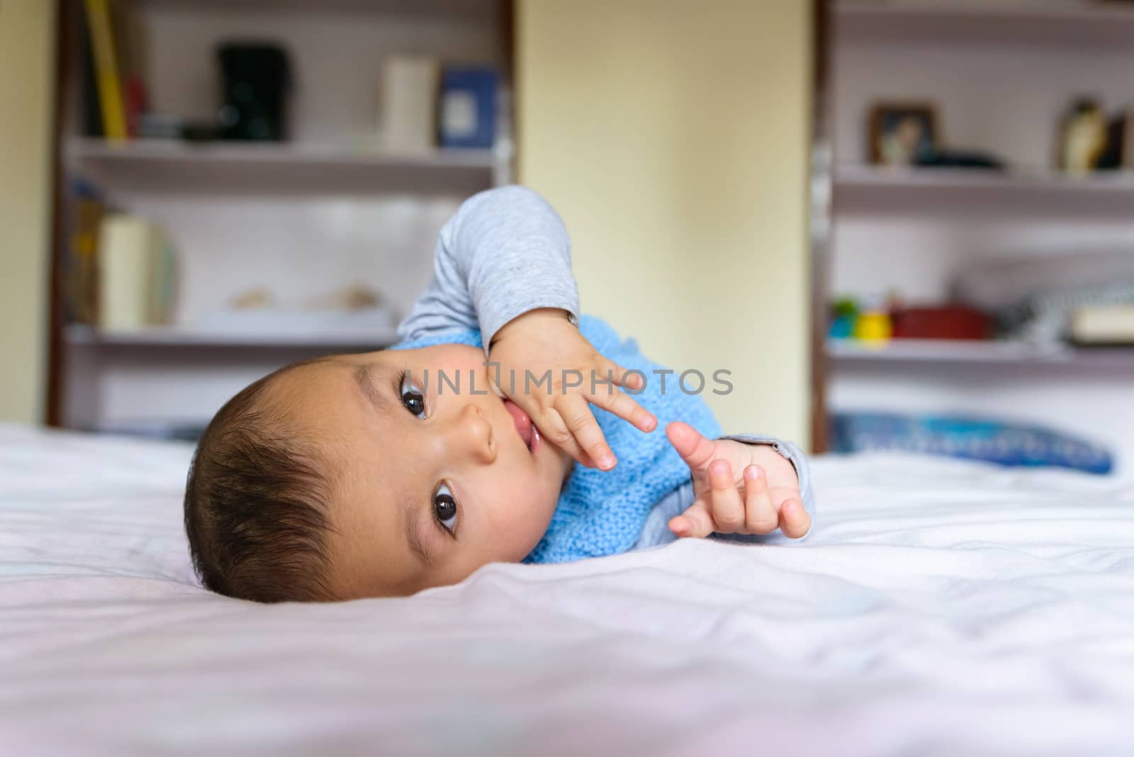 Eurasian baby lying on bed