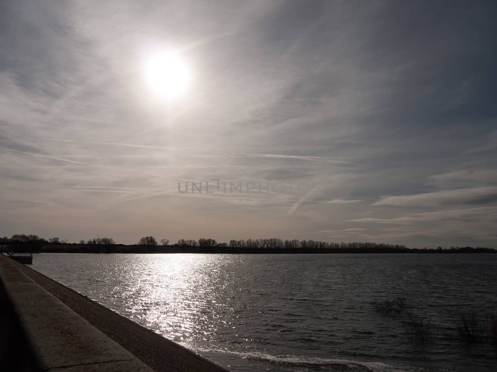 sunlight glare over open bay of water outside nature reserve landscape; essex; england; uk