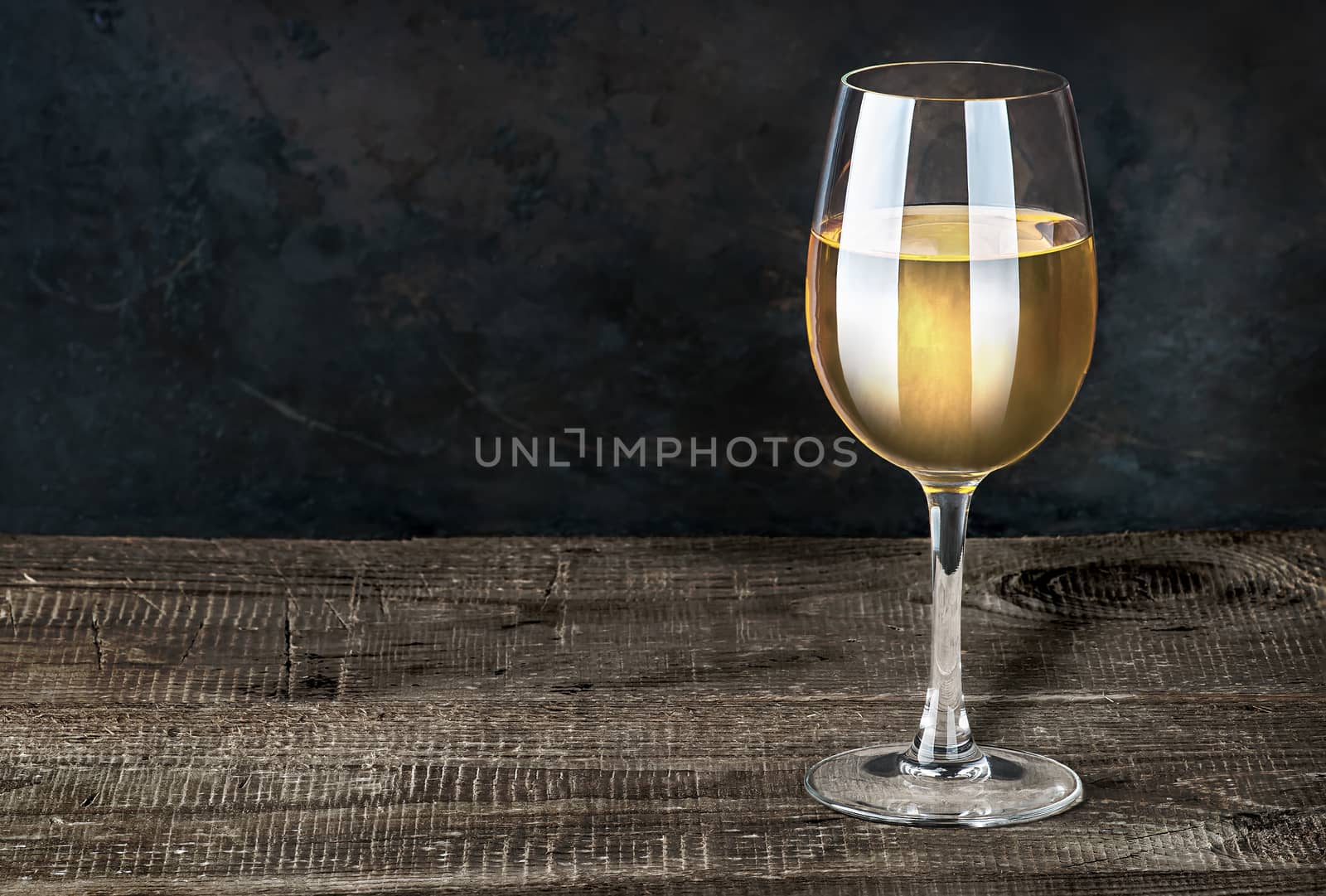 Glass of white wine on a wooden table. Dark background. Wooden table of plates.