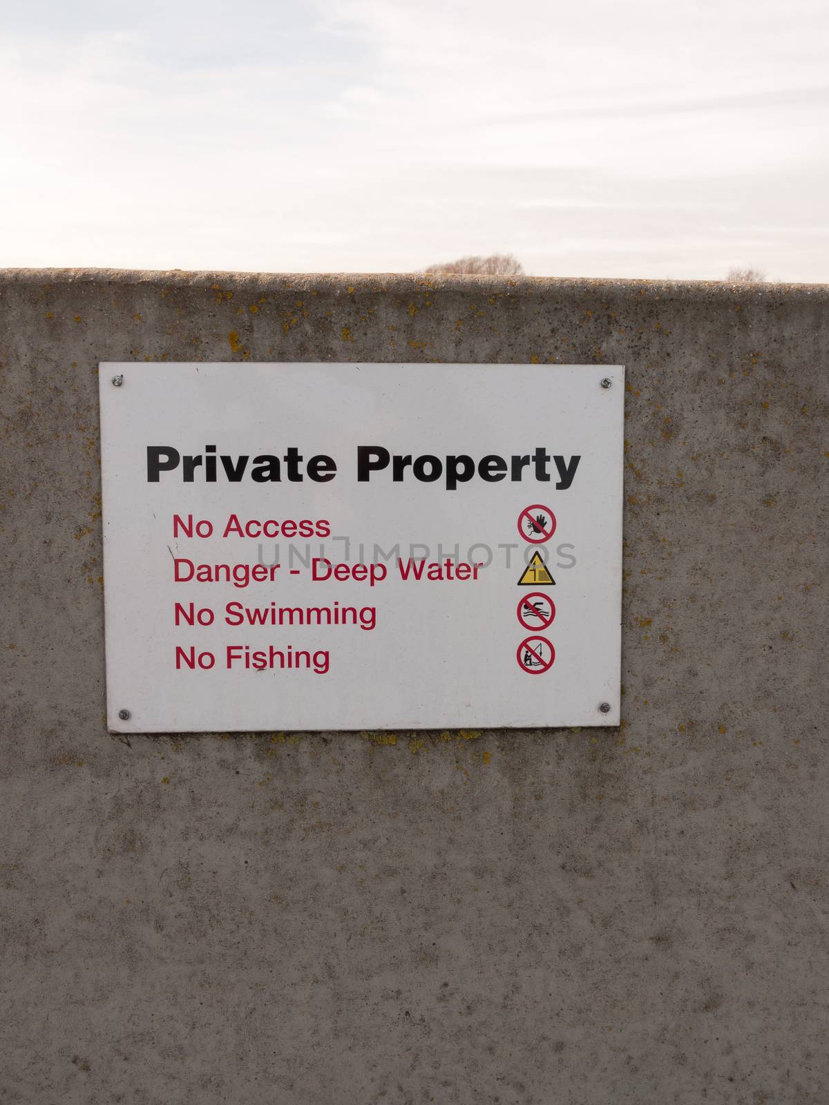 private property sign on grey sea wall barricade no permission; essex; england; uk