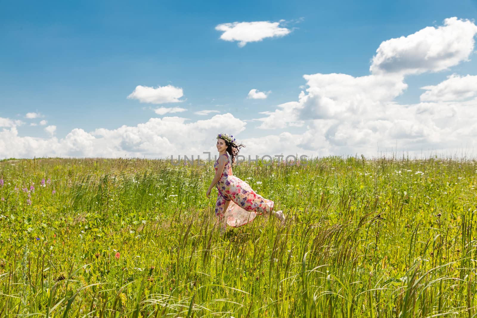 Portrait of the beautiful girl running in the field