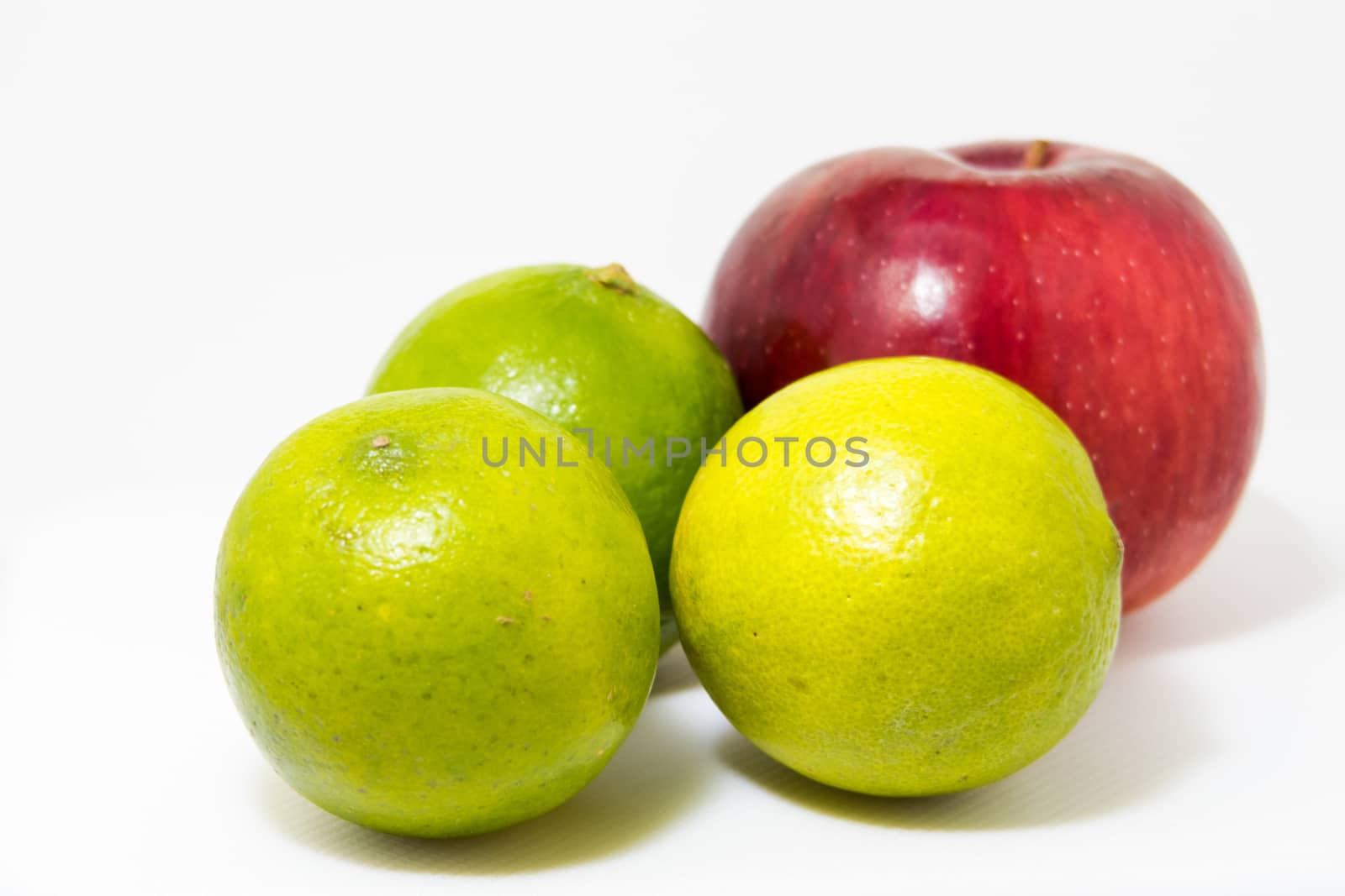 One red apple and three green lime isolated on white at shallow depth of field