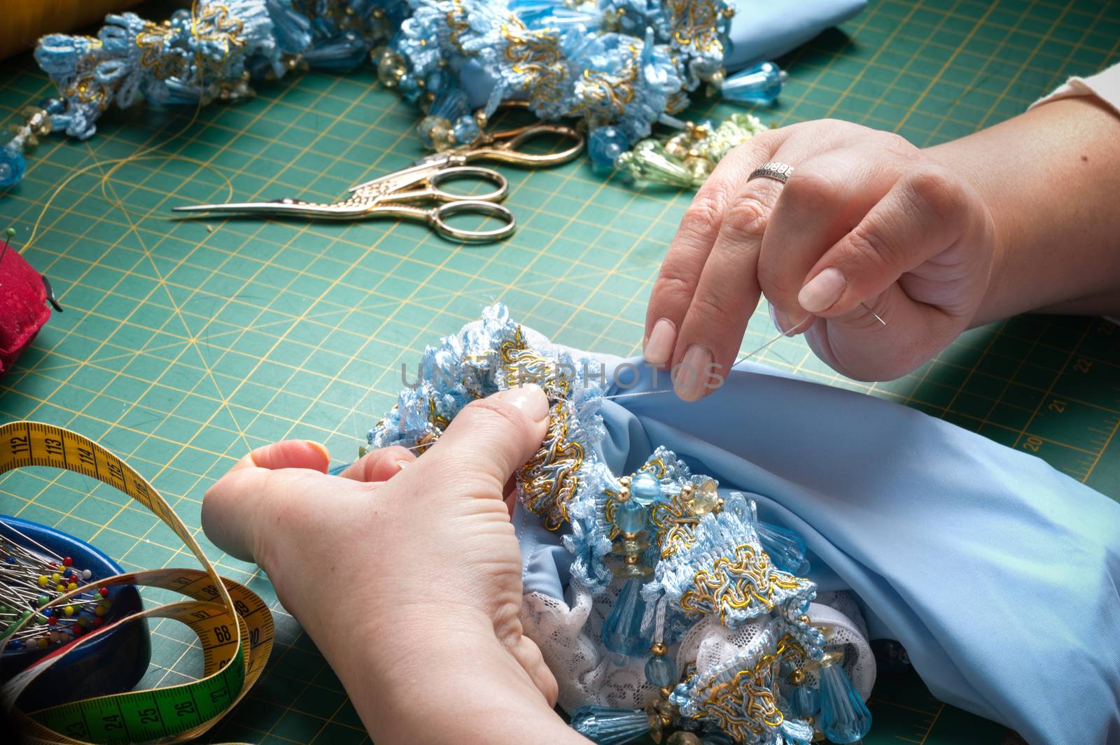 A woman sews a decorative element to clothes with a needle