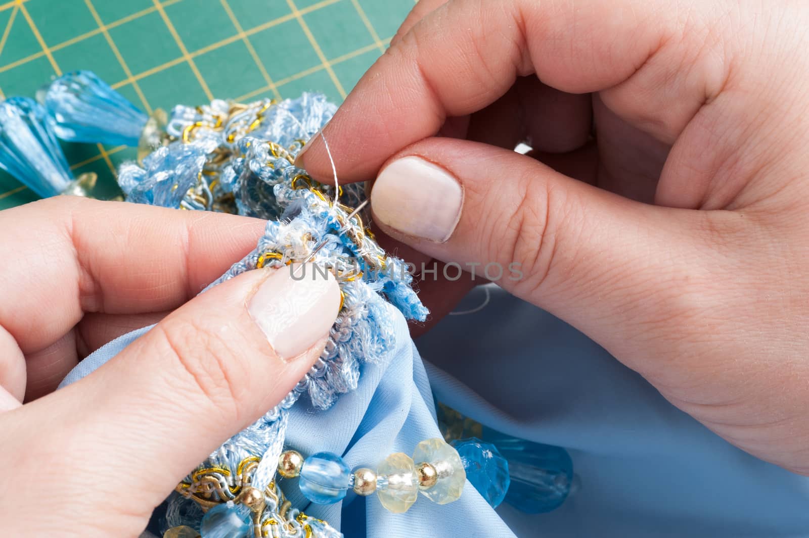 A woman sews a decorative element to clothes with a needle