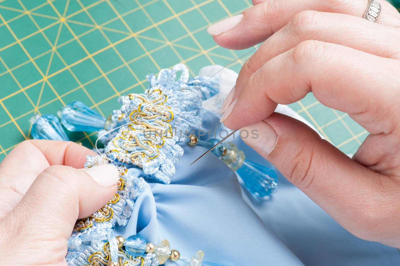 A woman sews a decorative element to clothes with a needle