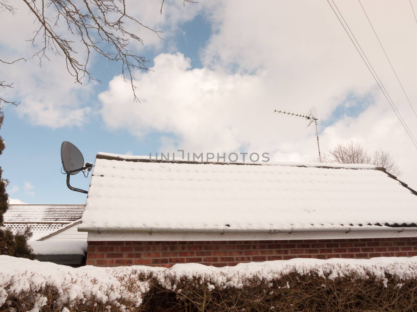 snow covered roof outside with black satellite dish; essex; england; uk