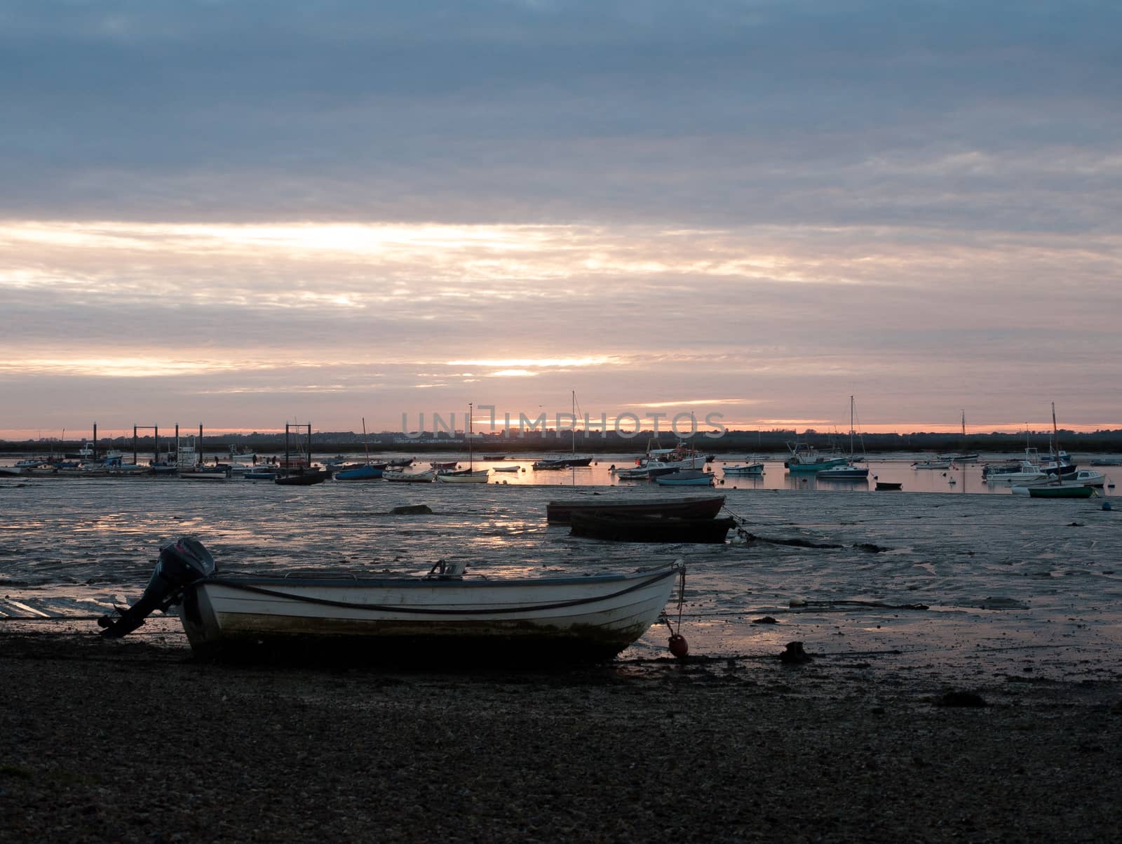 sunset over moored private wooden boats on coastline shore; essex; england; uk