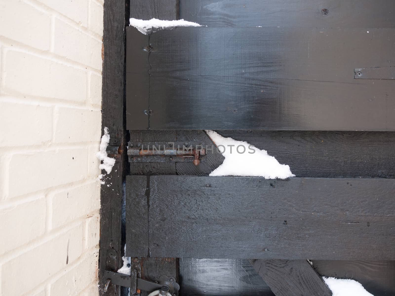 closed black gate with metal bolt with snow; essex; england; uk