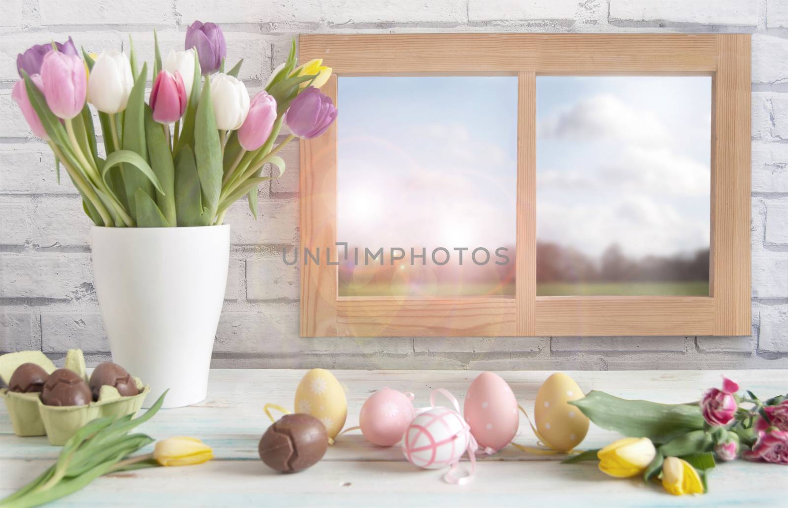 Easter eggs and spring flowers in a vase next to a window 