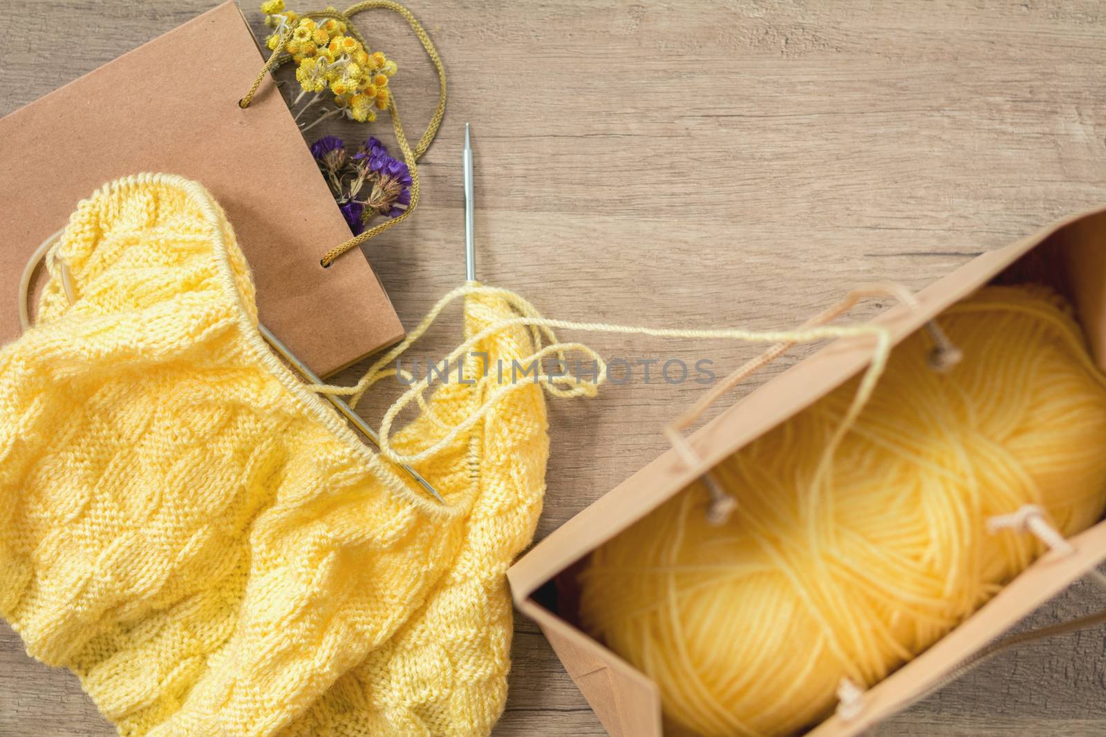 Light yellow knitting wool and knitting needles on wooden background. Top view.copy space. Knitted fabric and yarn on a wooden surface.