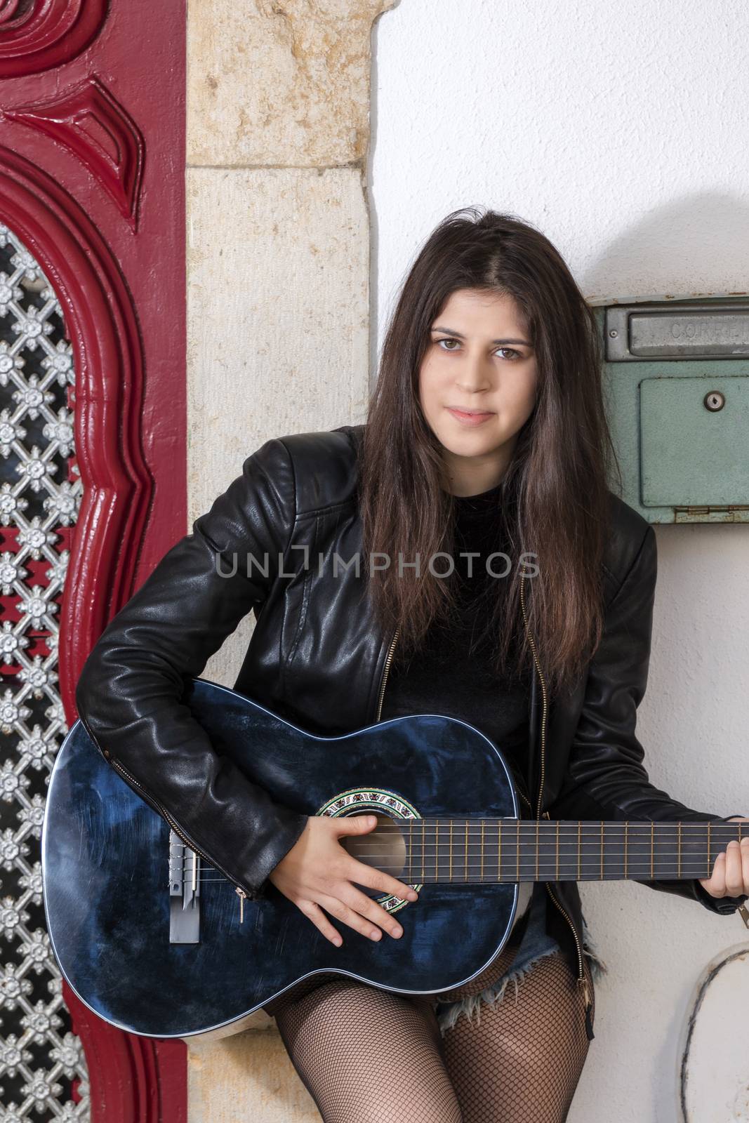 Close view of a beautiful young woman with classic guitar on the streets of the city.