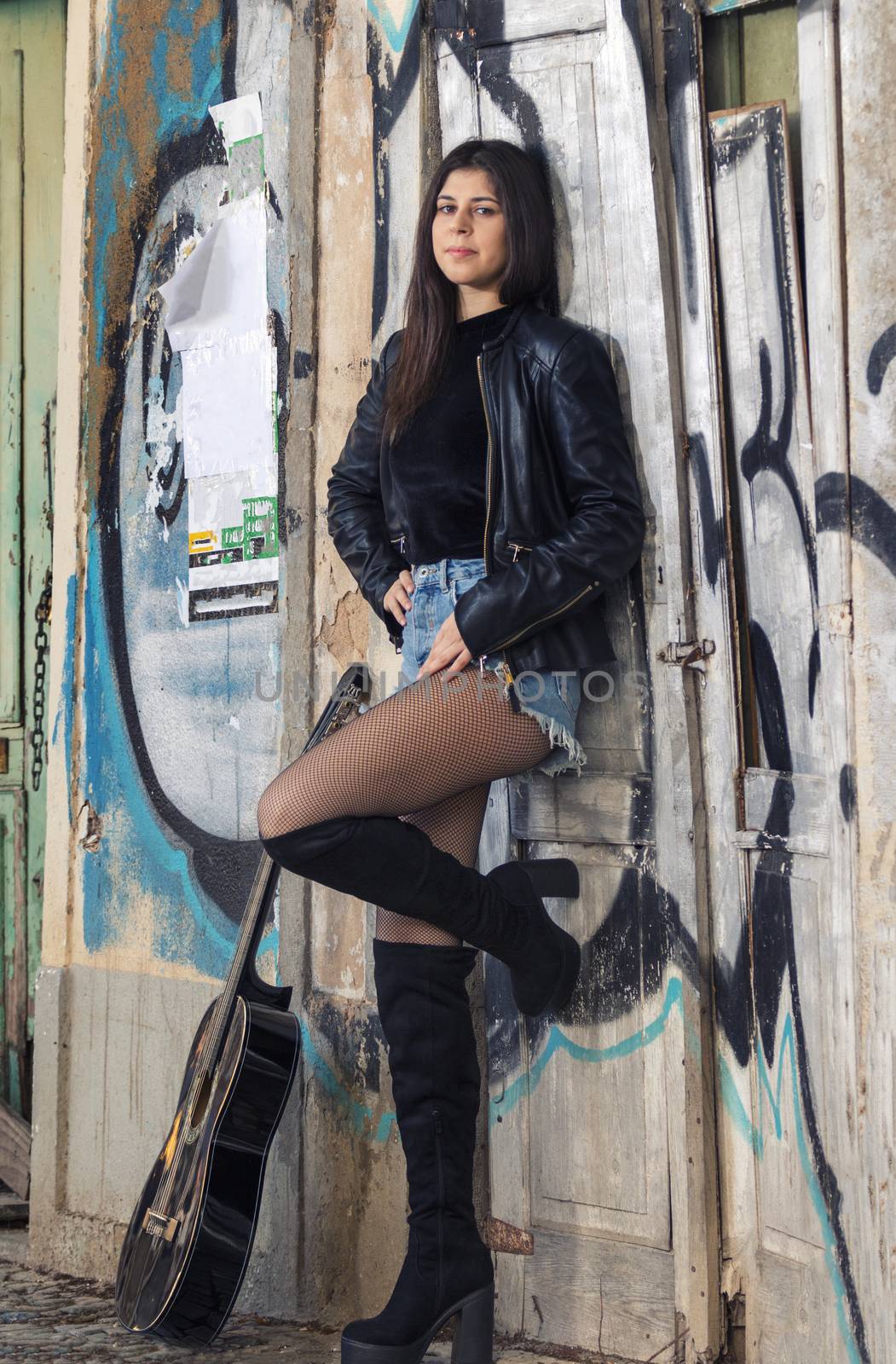 Close view of a beautiful young woman with classic guitar on the streets of the city.