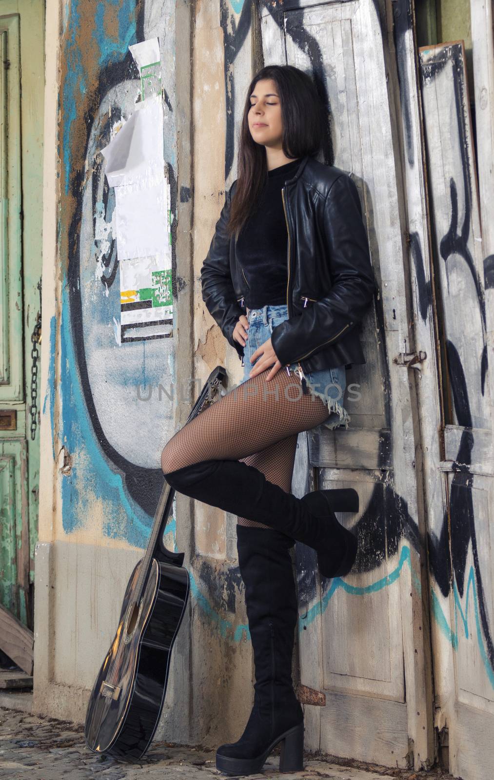 Close view of a beautiful young woman with classic guitar on the streets of the city.