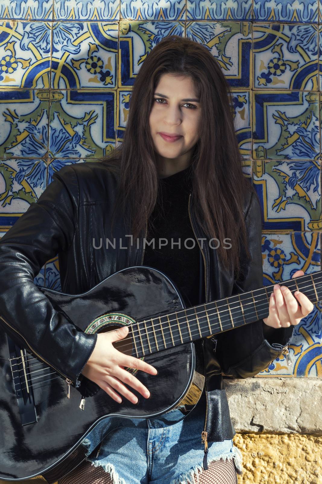 Close view of a beautiful young woman with classic guitar on the streets of the city.