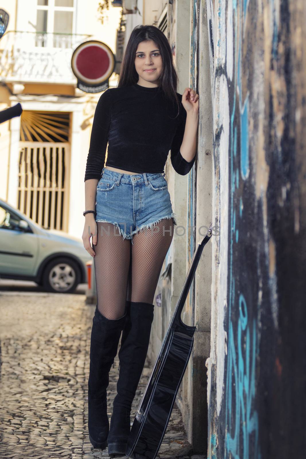 Close view of a beautiful young woman with classic guitar on the streets of the city.