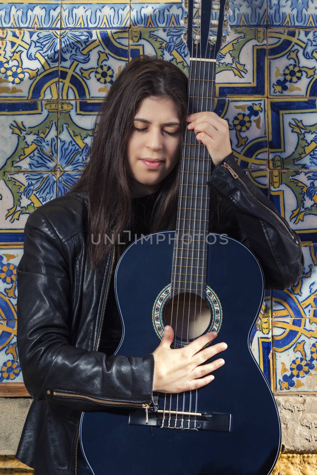 Close view of a beautiful young woman with classic guitar on the streets of the city.