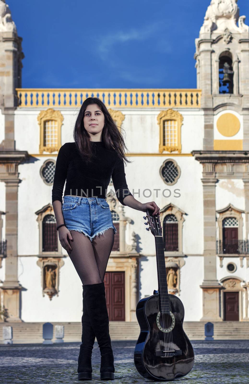 Close view of a beautiful young woman with classic guitar on the streets of the city.